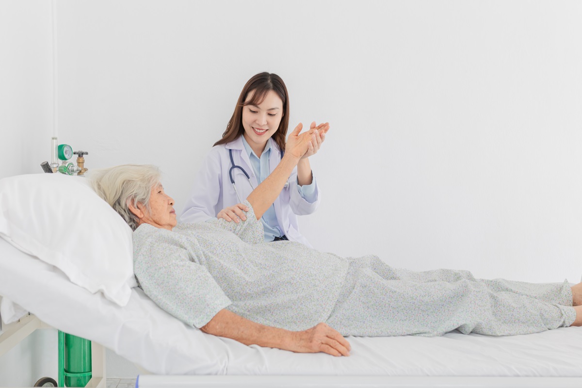 Asian,Female,Doctor,Comforting,Elderly,Patient,In,Hospital,Bed,,Holding
